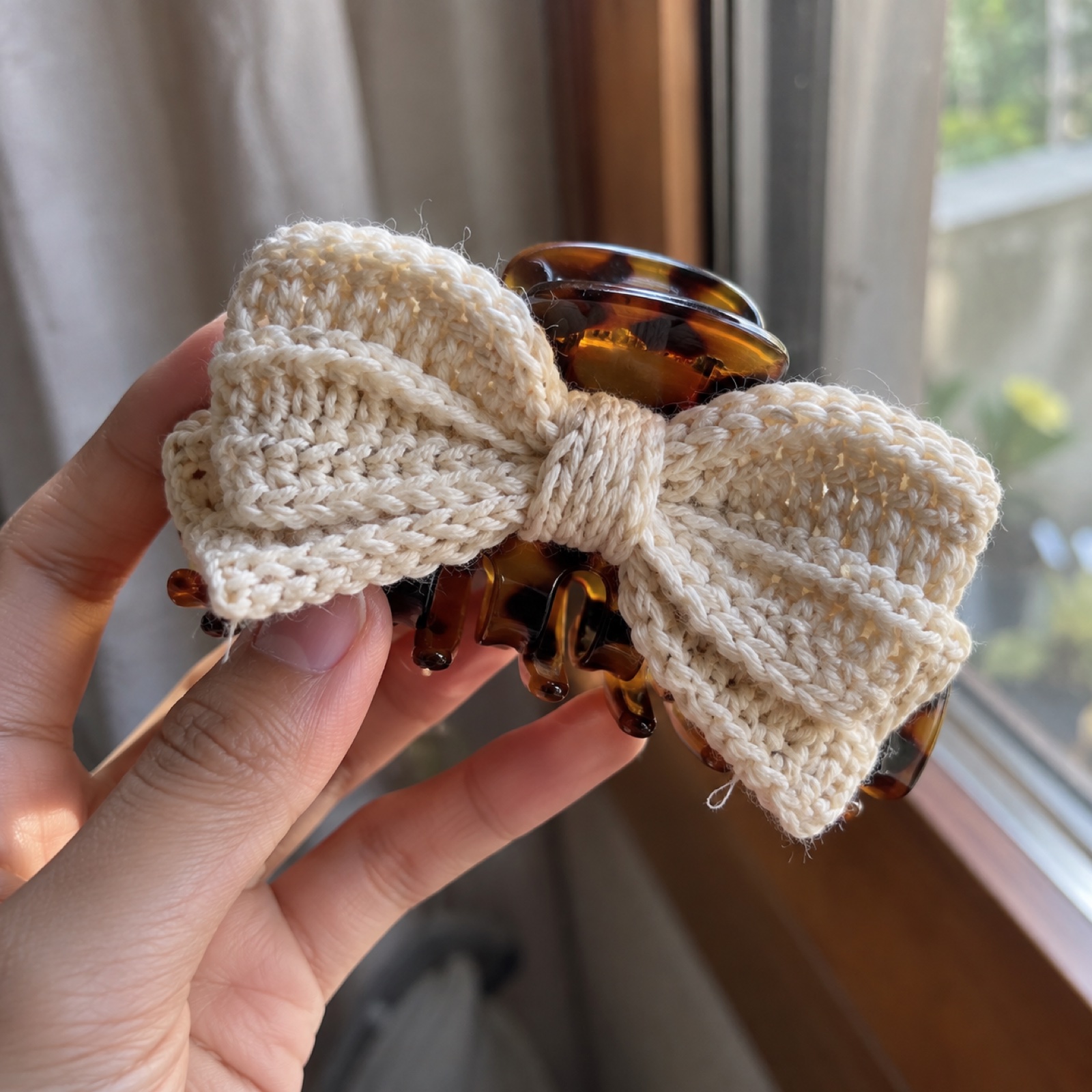 Close-up of the cream bow loops sitting on the tortoiseshell claw on the Bow Claw Clip