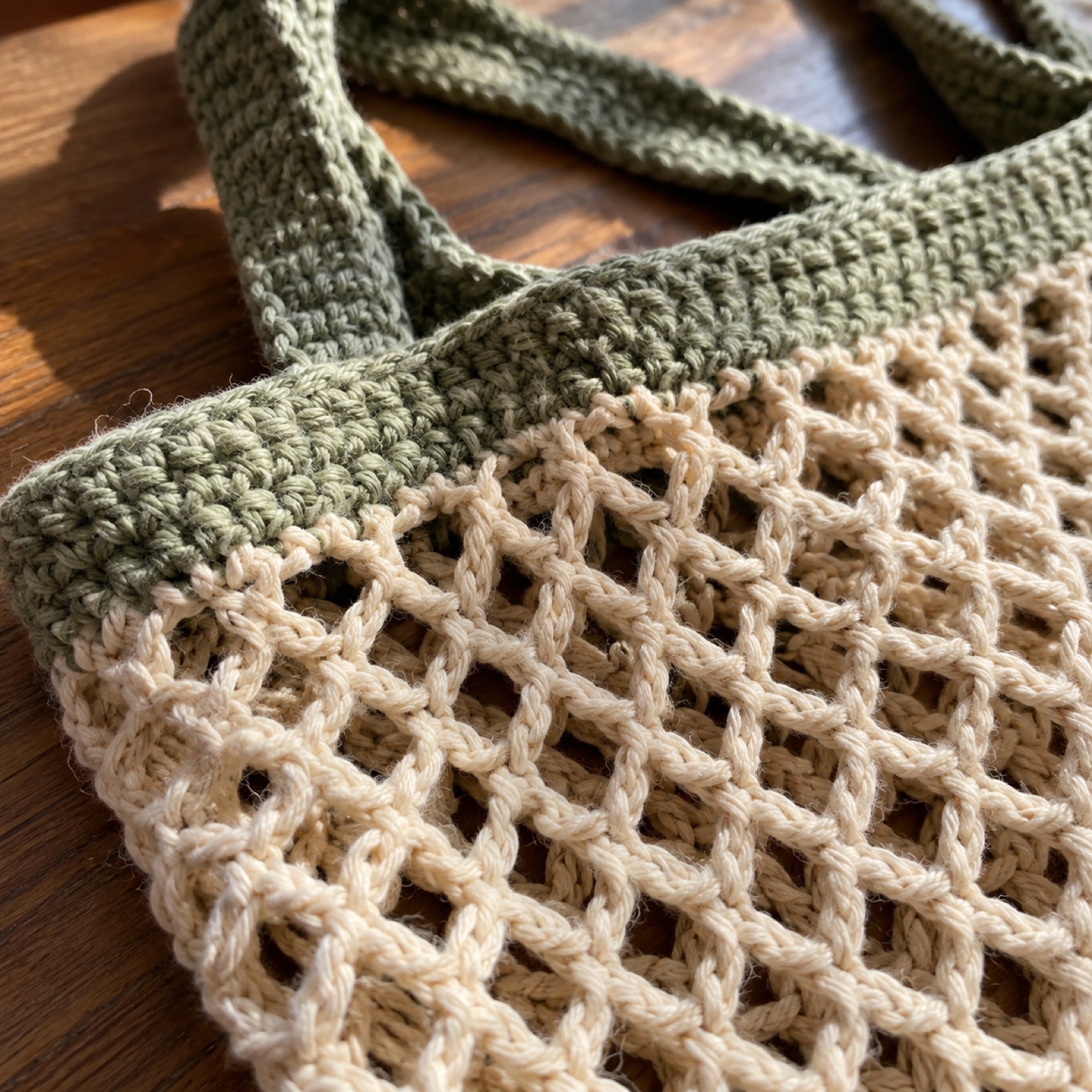 Close-up of the open chain-mesh grid meeting the solid sage rim on the Market Mesh Tote