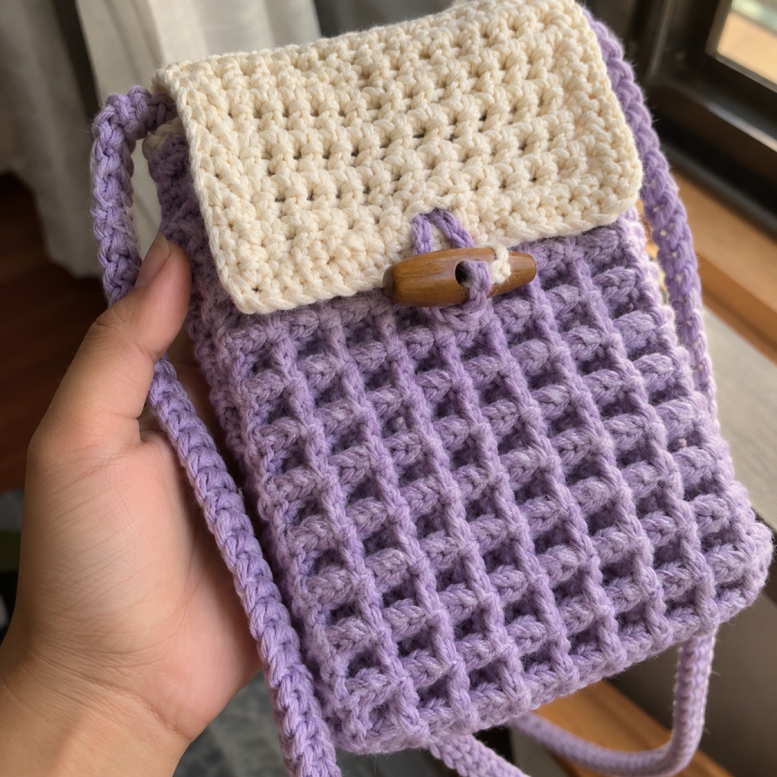 Close-up of the waffle-stitch texture beside the wooden toggle on the Crossbody Phone Bag