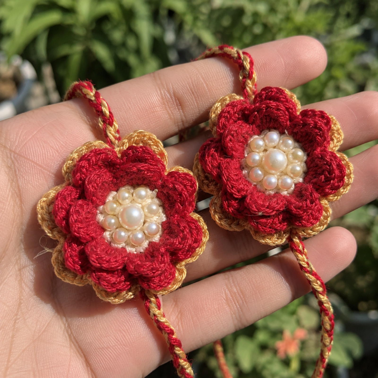Close-up of the layered red petals and pearl bead centre on the Crochet Rakhi Pair