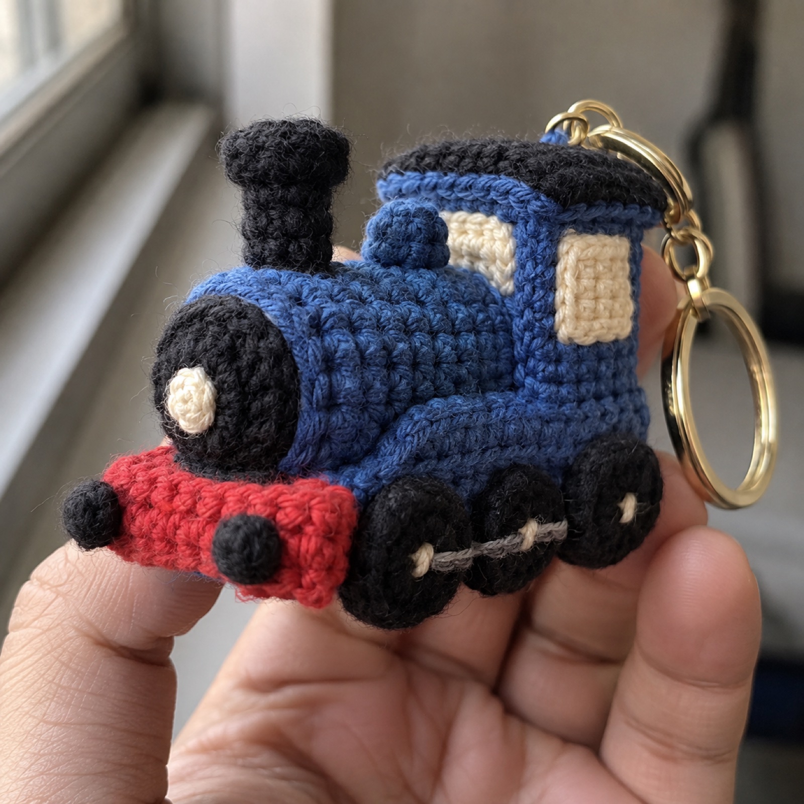 Close-up of the little black wheels and red buffer beam on the Toy Train Keychain