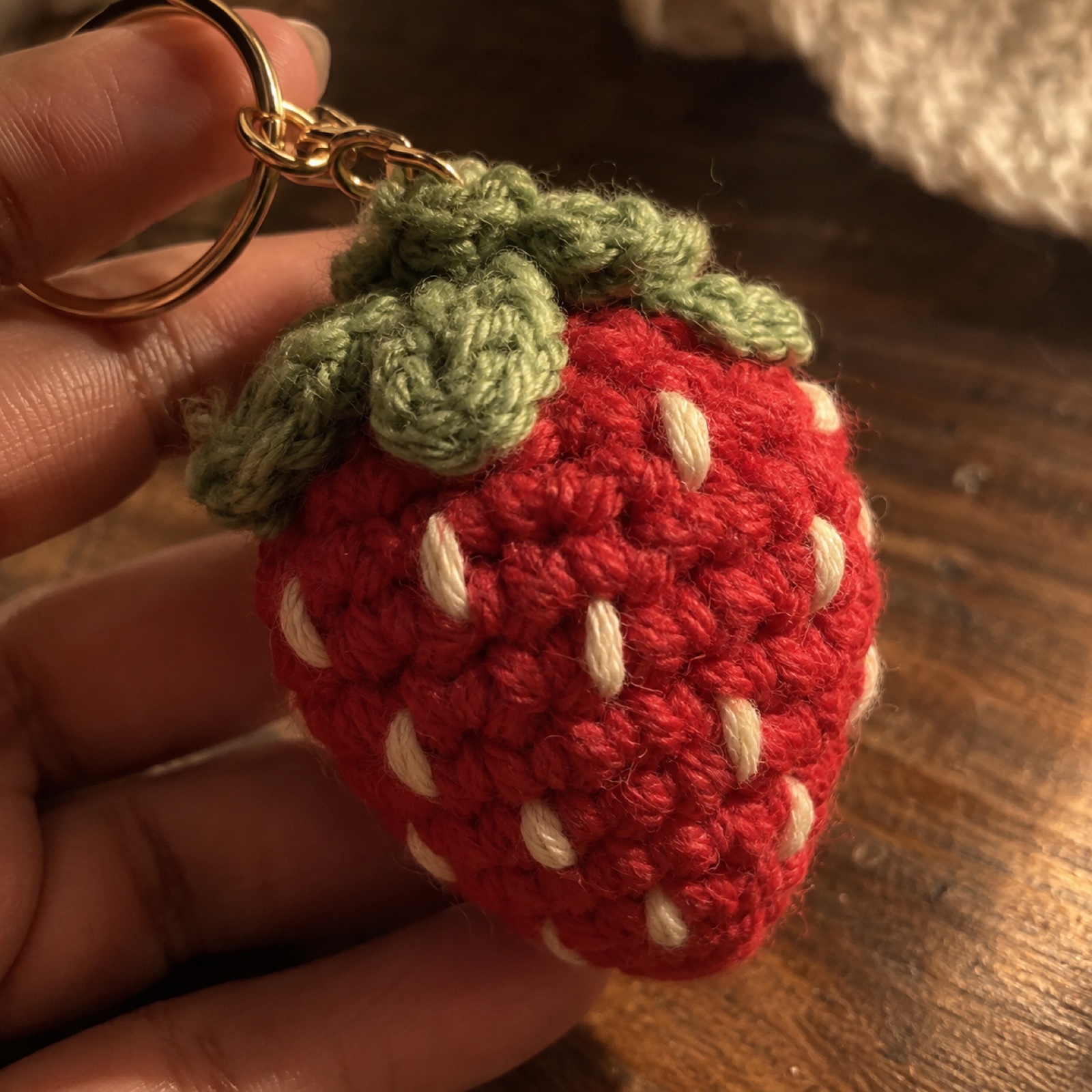 Close-up of the cream seed stitches and leaf cap on the Strawberry Keychain