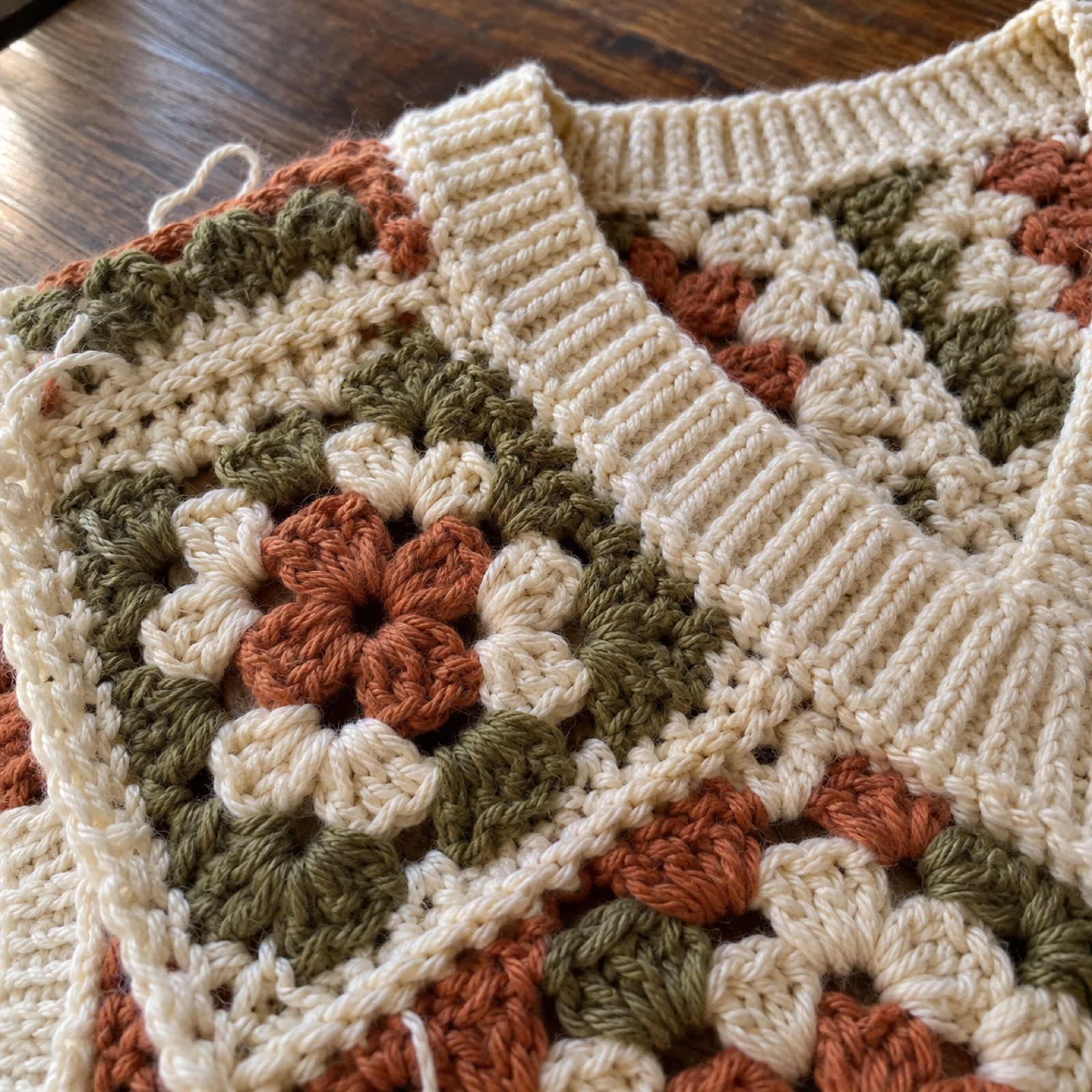 Close-up of the ribbed V-neck edge beside a granny square on the Granny Square Vest